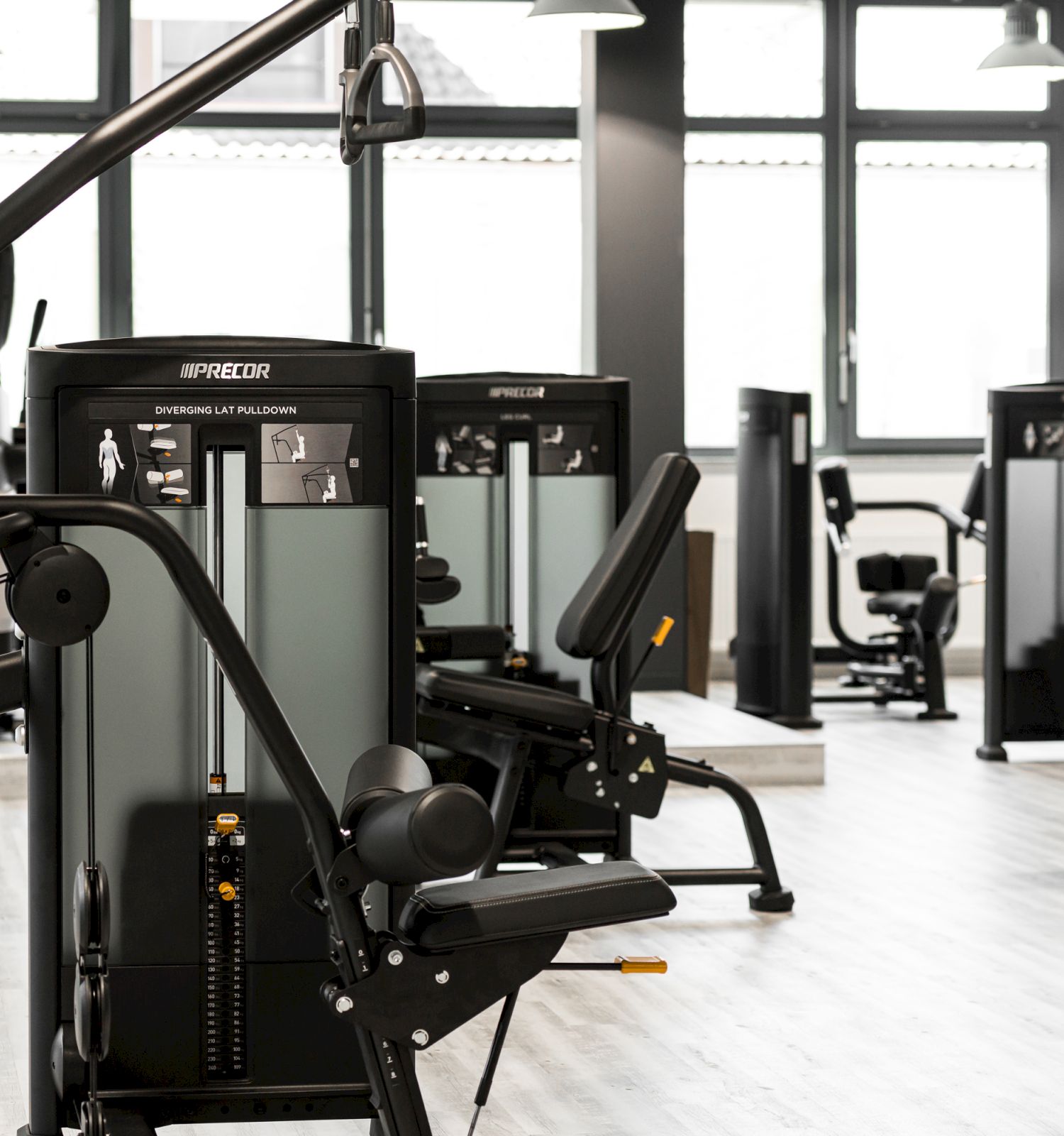 A modern gym with various exercise machines, including leg and cardio equipment, arranged in a spacious, well-lit room.