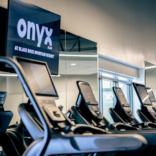 A row of people working on laptops at a crowded tech event or cafe, with a blue &ldquo;OPEN&rdquo; sign and banners in the background.