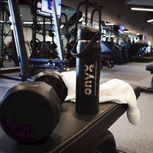 Person lifting weights in a gym with equipment and mirrors; someone lying on a bench while others exercise. Top it at 140 characters, ending with a period.