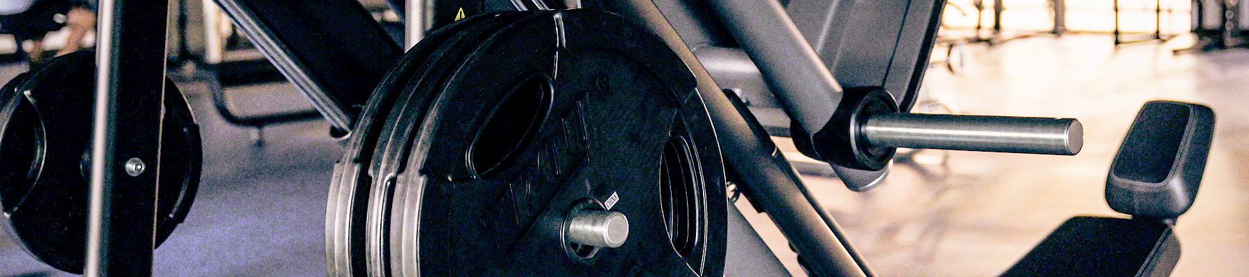 A heavy squat/leg press machine with stacked weight plates in a gym, ready for leg workouts.