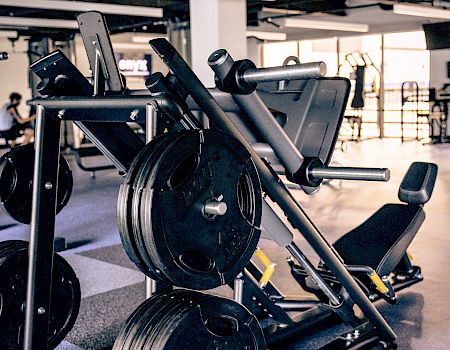 A heavy squat/leg press machine with stacked weight plates in a gym, ready for leg workouts.