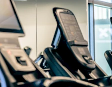 A row of treadmills in a gym with a big sign reading “Only” in the background.