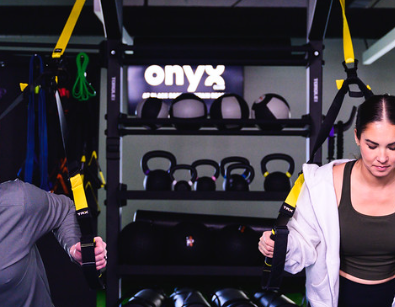 Two people do cable-machine workouts in a gym, pulling handles as part of a strength training exercise.